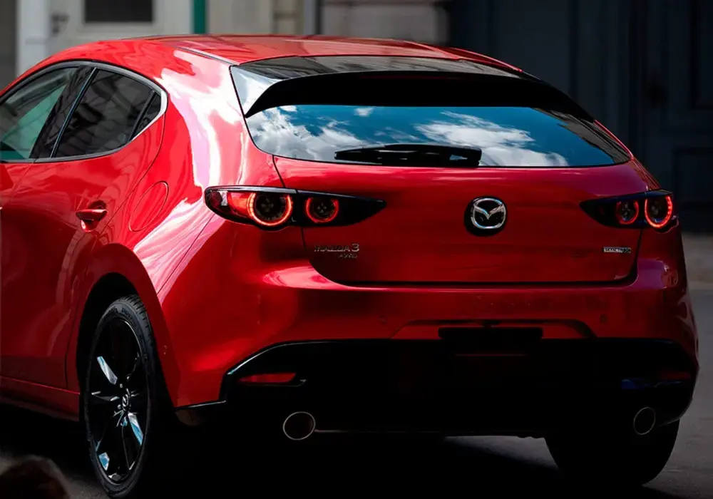 Mazda 3 Sport de color rojo estacionado en una calle urbana, vista trasera